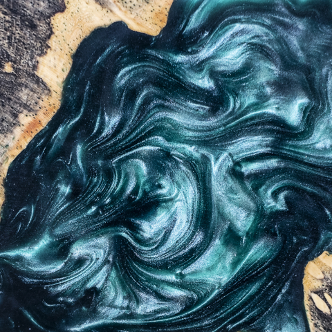Pigmented epoxy resin swirling on a contained wooden surface