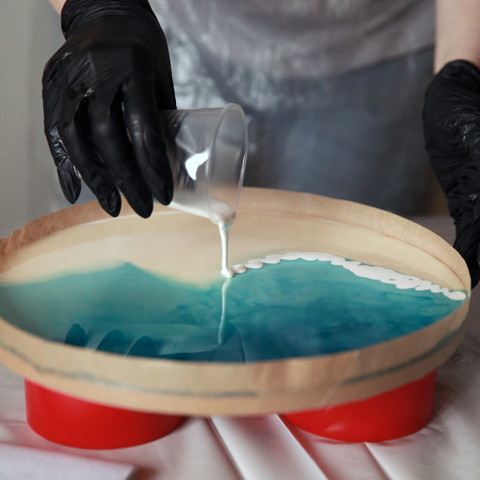 White pigmented epoxy being poured over an art project