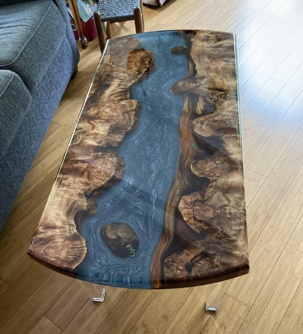 A deep pour epoxy river table with blue tinting to convey a river theme.