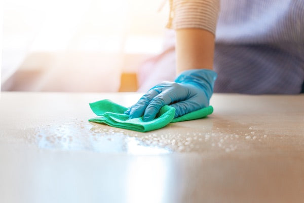 A gloved hand cleaning an epoxy surface with soapy water and a cloth.