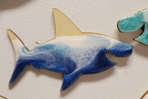 A shark-shaped piece of resin art with an epoxy resin finish colored and manipulated to look like ocean waves.
