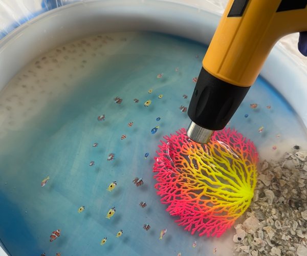 A heat gun being used on a sea-themed resin art piece.