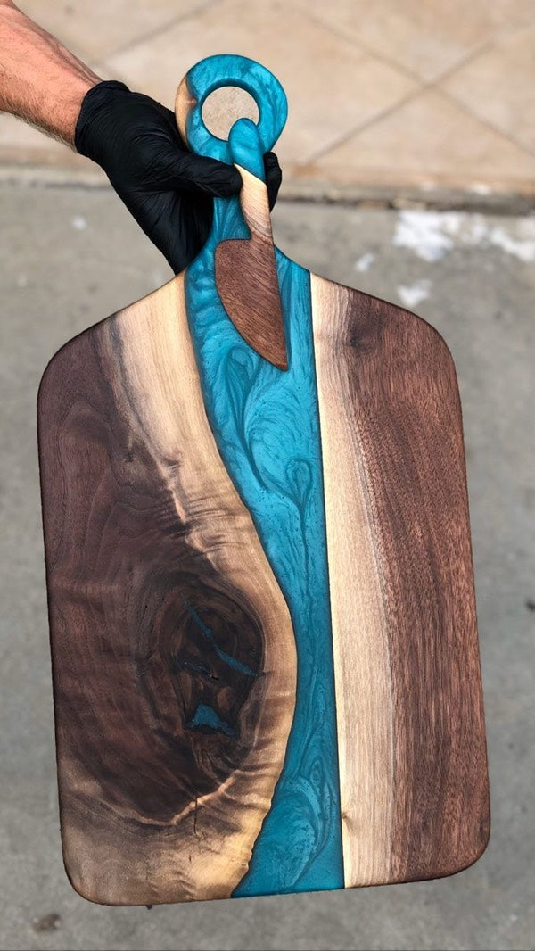An epoxy charcuterie board with a handle grip and vibrant blue hue