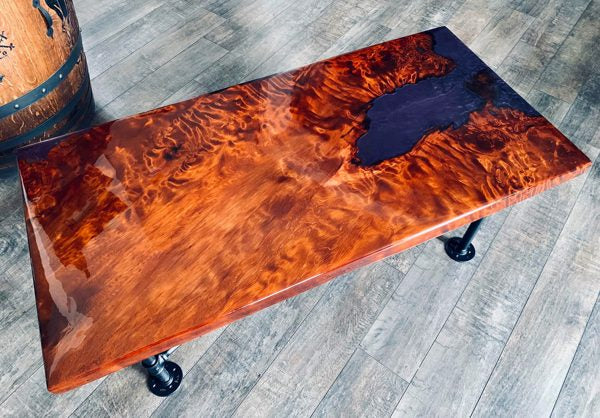 An epoxy river table with a pooling black vein surrounded by orange