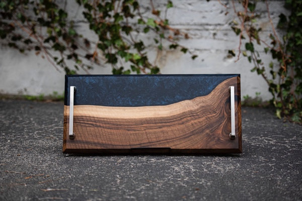 An epoxy serving tray with night sky pattern adjacent to contrasting wood tones.