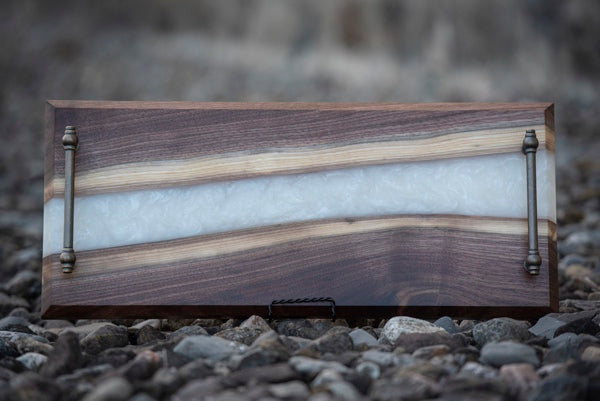 An epoxy serving tray with a pale ice layer running through the center of the wooden grooves.