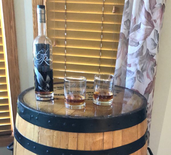 A barrel table top coated with a layer of UltraClear Table Top Epoxy. Resting on its lid are two small glasses and a bottle.