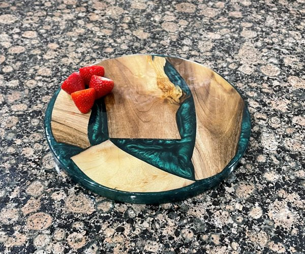 An epoxxy resin charcuterie board, made with a light-colored wood and blue-tinted epoxy resin.