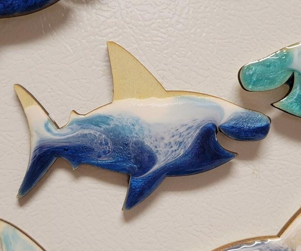 An epoxy resin art piece that looks like a shark colored with an ocean-themed resin layer and tint.