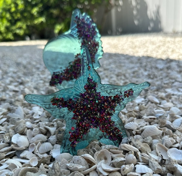 Two sea-themed epoxy resin decorations, tinted with blue Pigmently Dyes and embedded with glitter.