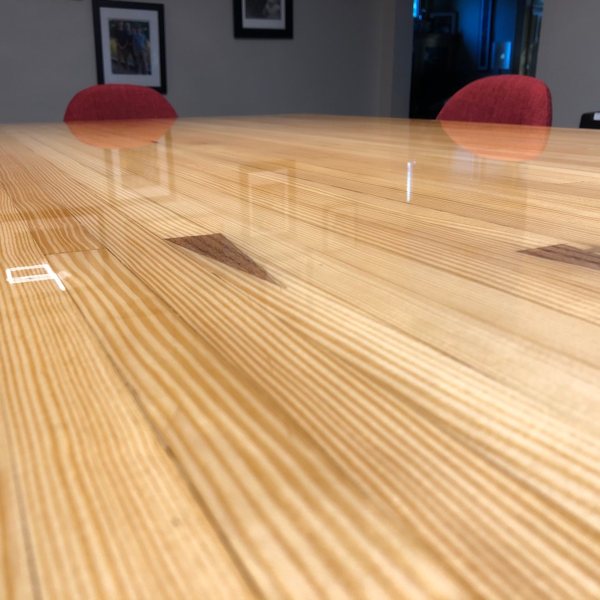 A close-up of a wooden epoxy table top surface, seen from a steep angle to showcase the smoothness of the resin finish.