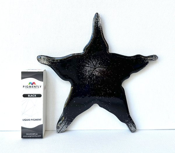 A resin art piece shaped abstractly like a star and tinted black with Black Epoxy Dye from Pigmently.