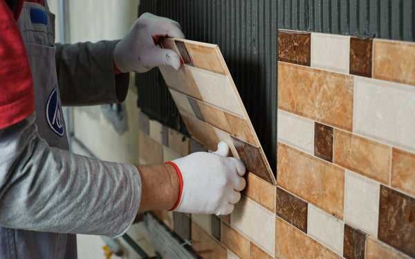 tiler installing ceramic tiles to a kitchen wall