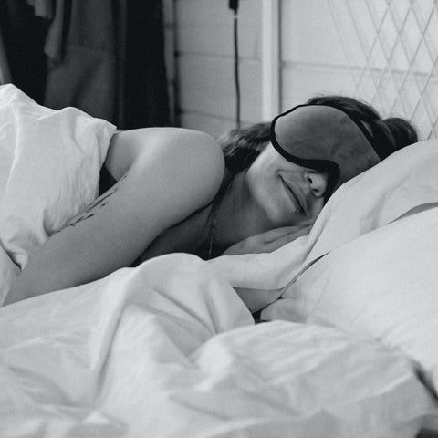 woman sleeping by herself wearing a sleep mask black and white picture