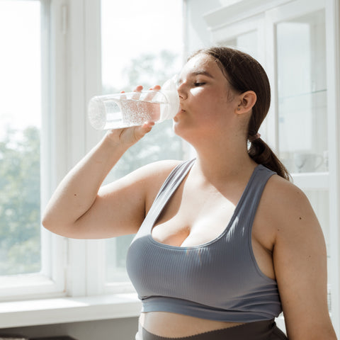woman drinking water bottle after working out