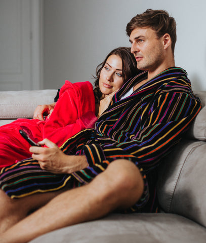 man and woman in bathrobes watching tv