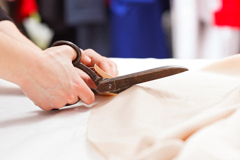 A tailor cutting fabric with sewing shears 