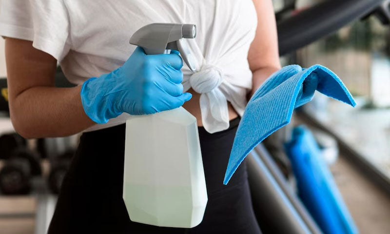 woman with gloves holding cleaner