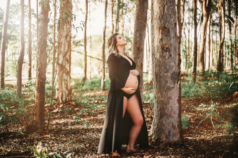 Pregnant woman holding her stomach in the forest