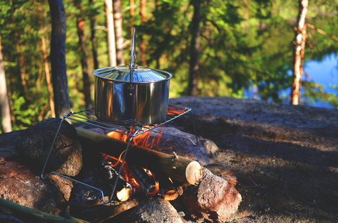 Cooking a pot over wood fire while out camping 