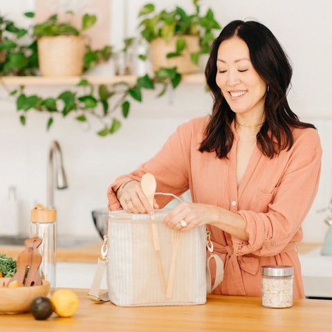 Woman adding bamboo cutlery to the back pocket of her lunch bag