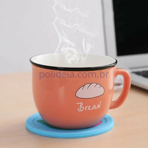 aquecedor de xícaras e caneca de silicone conectado a um cabo USB e uma xícara de café sobre ele. (