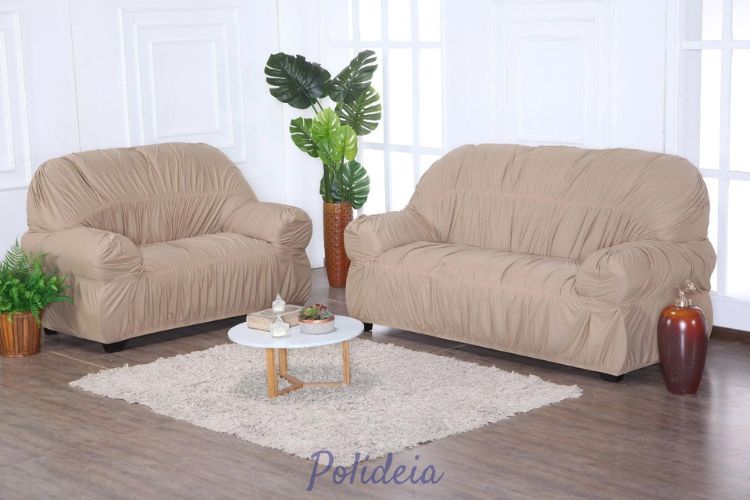 Uma foto de um sofá de dois lugares coberto por uma capa cinza clara com almofadas coloridas.