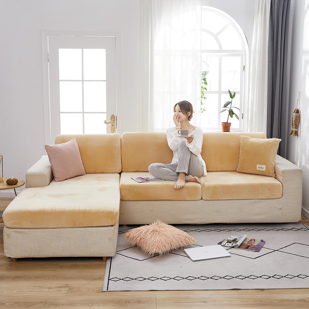 Capa de sofá de veludo spandex na cor azul marinho, cobrindo um sofá de três lugares com almofadas brancas. A capa tem um ajuste perfeito e um toque macio.