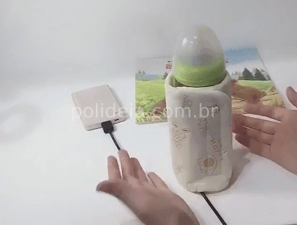 aquecedor de mamadeira portátil USB envolvendo uma mamadeira com leite e conectado a um carregador de celular