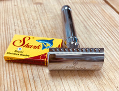 double edged metal razor laid next to a box of razor blades