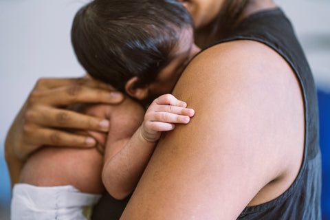 An infant is cradled in their parents' arms