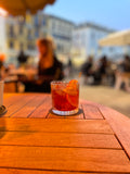 Negroni on a wood table over looking a roman piazza. 
