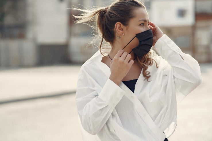 woman wearing white shirt putting a mask