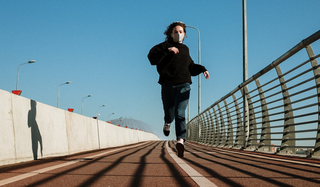 a woman running while wearing a face mask