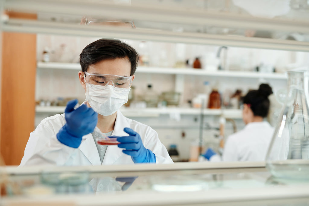 a man wearing white coat, white mask, and blue gloves