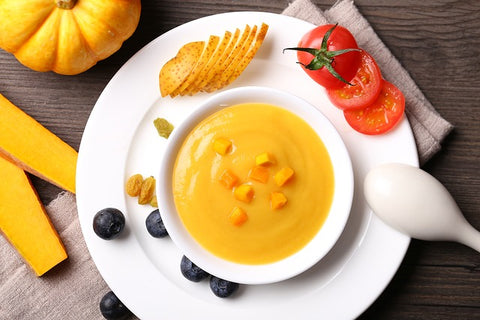 Pumpkin puree in a white bowl with a spoon on the edge