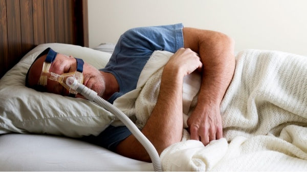Man sleeping while breathing through a CPAP machine