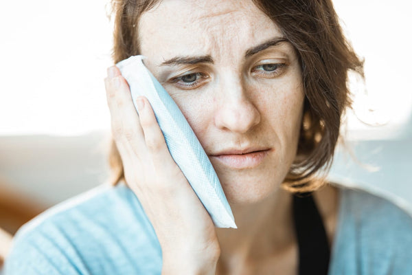 Woman holding her sore jaw with heatpad