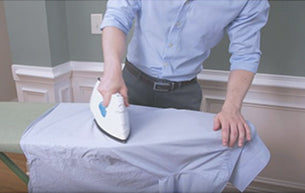 man ironing blue dress shirt