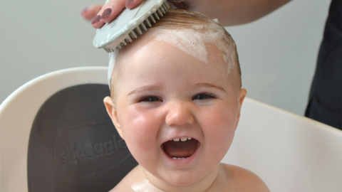 Baby in shnuggle bath with hairbrush