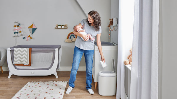 Mum holding baby dropping nappy into Eco Touch Nappy bin