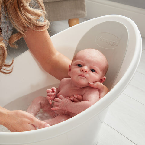 newborn in baby bath held by mum