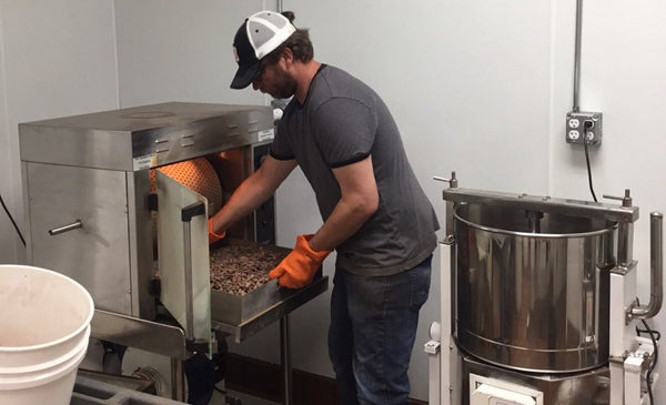 person taking out roasted cacao beans from roaster