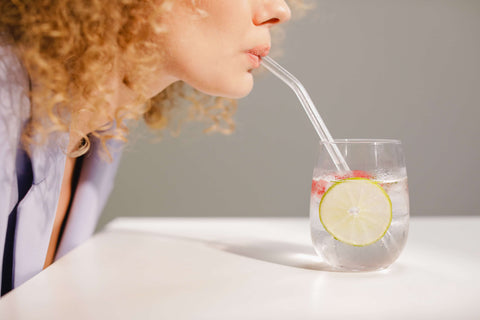 A woman sipping from a glass with a reusable glass straw