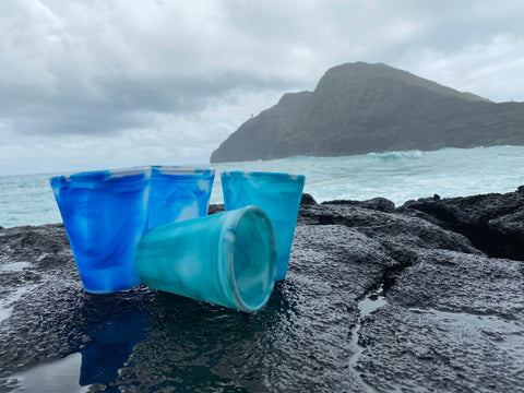 Four Gosili Silicone Ocean Cups sitting on a rock with the ocean as background