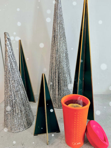 Reusable Silicone Gosili Cup filled with a Hot Toddy sitting in front of Christmas Decoration