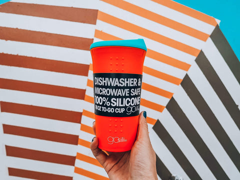 A reusable silicone tumbler with the tag on on a colorful background 