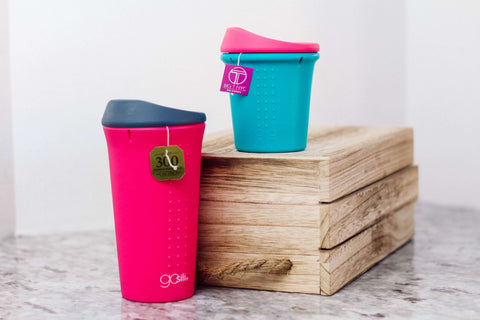 Two Reusable silicone tumblers sitting side by side with a tea string hanging on the side 