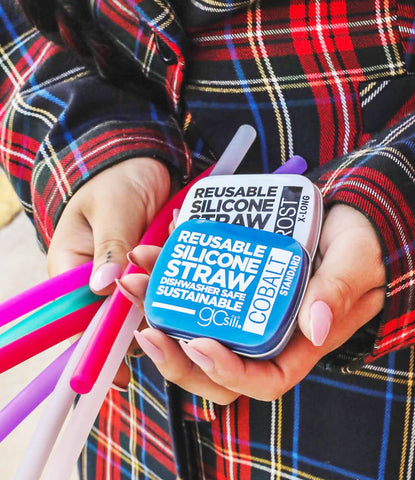 A women wearing a plaid button down shirt holding a bunch of silicone reusable straws on one hand and a travel case for the straws on the other hand