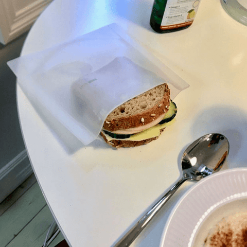 Reusable silicone bag sitting on a table with a sandwich in it. 